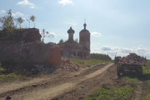 Прицеп с кирпичами рядом с разобранной стеной.